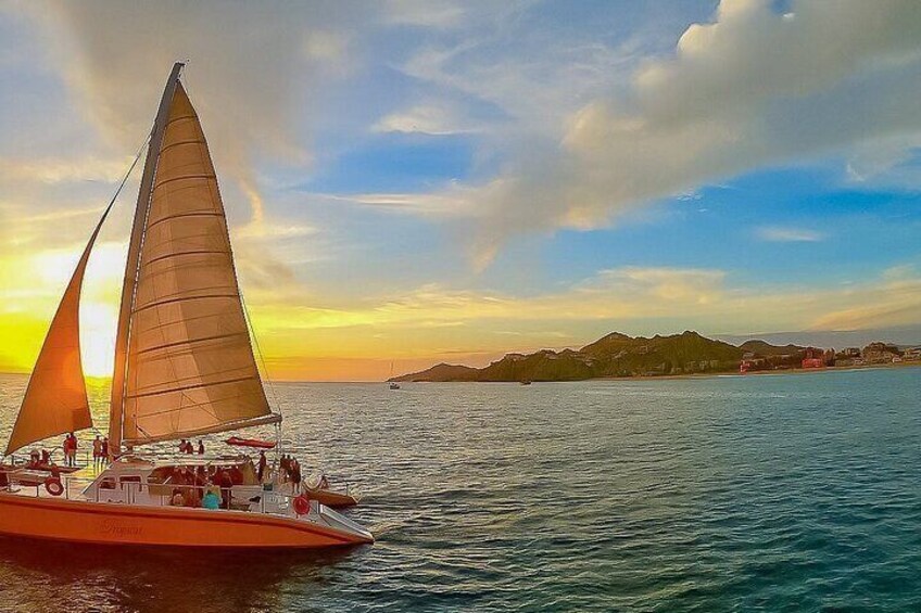A sailboat on calm waters with a sunset in the background and a distant mountain range. 3