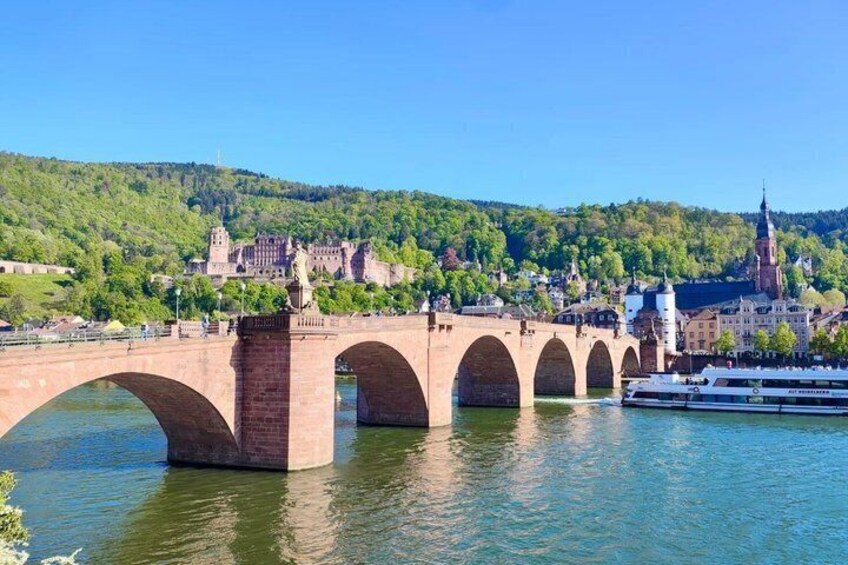 A stone bridge with multiple arches over a river, a boat, and a castle in the background. 3