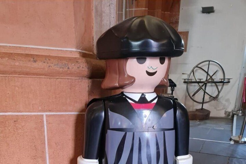 A statue of a person wearing a beret and a black outfit with a white collar. 2