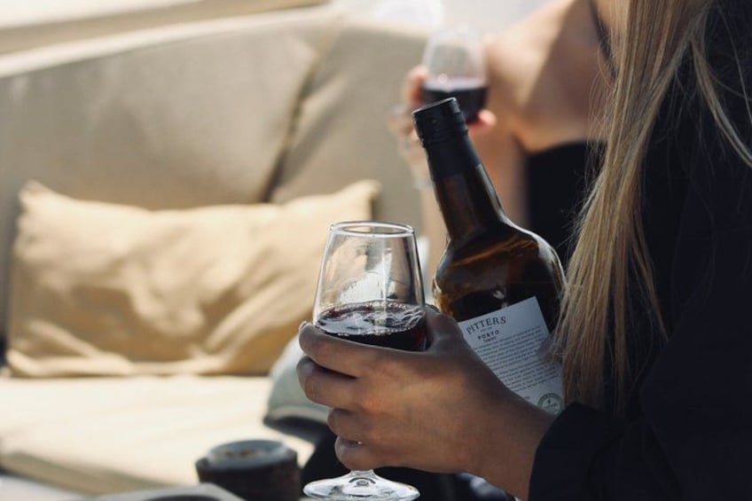 En person som håller i en vinflaska och ett vinglas och sitter i en soffa. 5