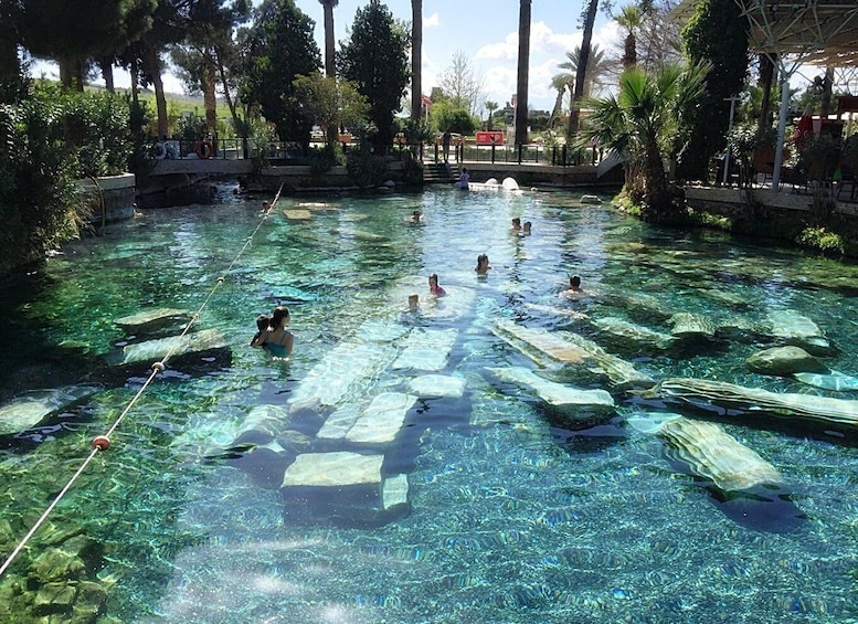 A clear pool with people swimming and floating on mats. 4