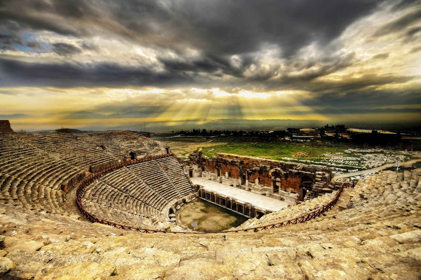 An ancient amphitheater with a central stage and tiered seating. 5