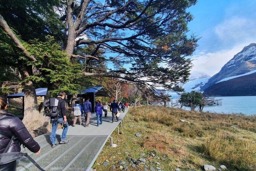 A pathway with people walking, a lake, and a mountain in the background. 5