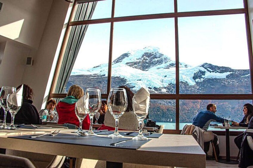 A dining area with tables set for a meal, large windows offering a view of snow-capped mountains. 2