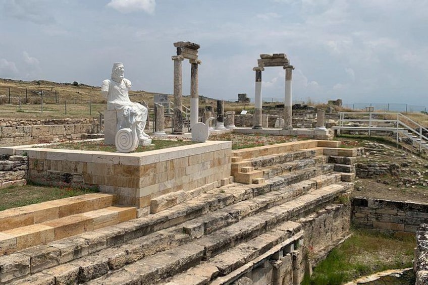 Ruinas antiguas con columnas y una estatua sentada. 2