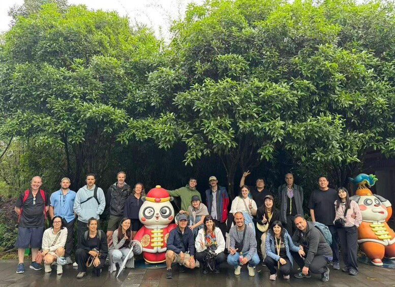 A group of people posing in front of a large tree and a statue of a character. 2