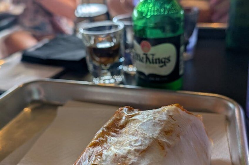 Une portion de friture sur un plateau, accompagnée d’une bouteille de bière Little Kings et d’un petit verre à liqueur en arrière-plan. 2