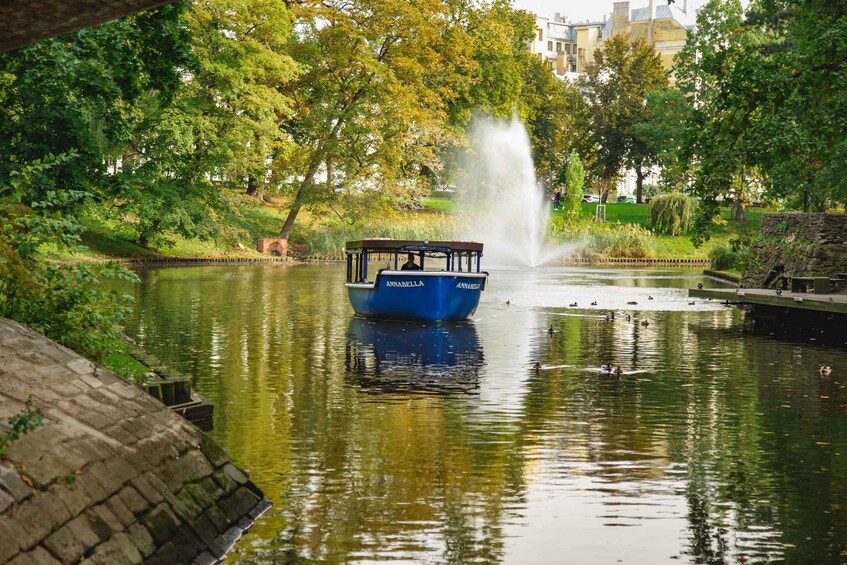 A blue boat named "Annabella" on a calm river with a fountain in the background. 2