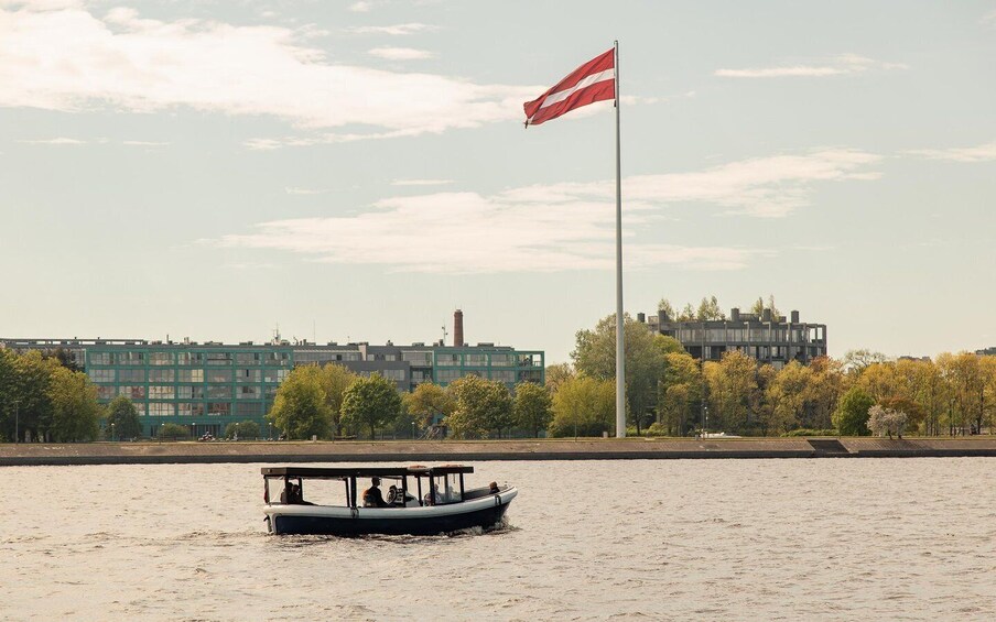 A boat on a river with a flag on a pole in the background. 3