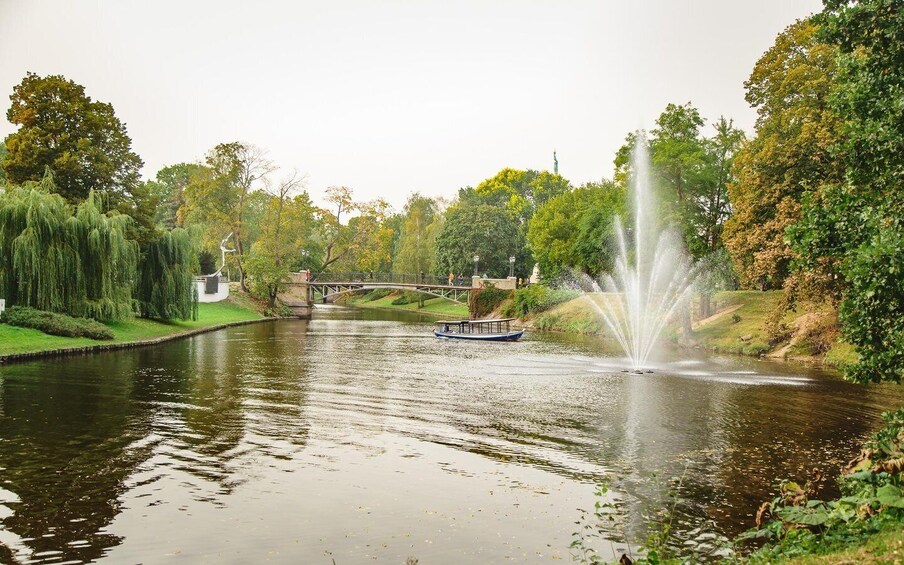A river with a bridge, a boat, and a fountain. 5