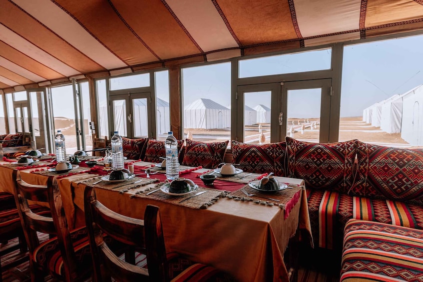 Un comedor con una mesa dispuesta para una comida, rodeado de cojines estampados y un techo de madera. 4
