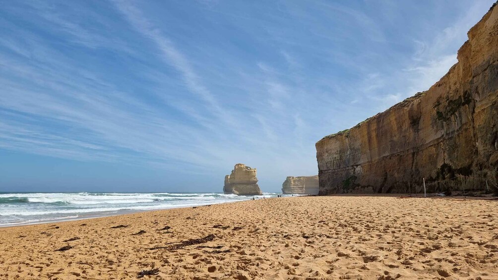 Una playa arenosa con grandes formaciones rocosas a lo lejos, bajo un cielo despejado. 4