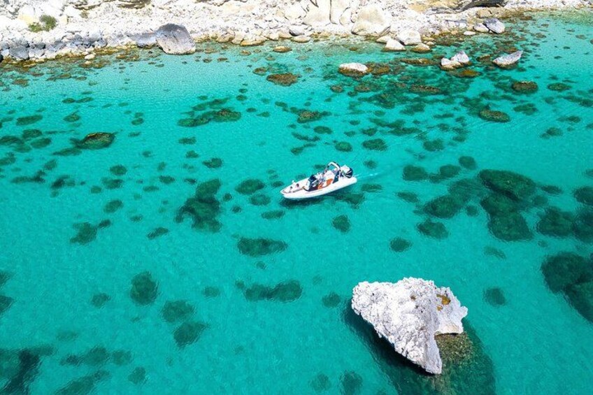 Un bateau sur une eau turquoise, où l’on voit clairement le fond marin, entouré d’un paysage rocheux. 5