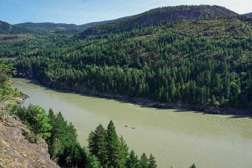 A river winding through a densely forested valley with hills in the background. 2