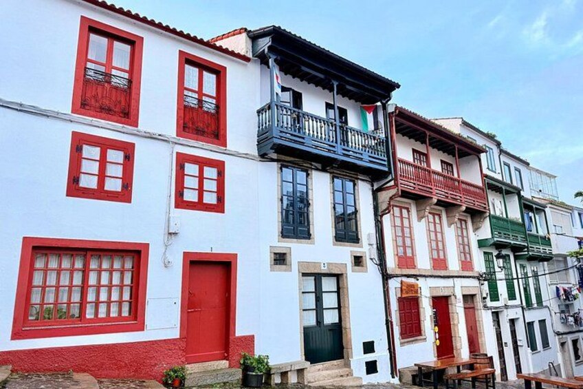 A row of colorful buildings with red and white facades, balconies, and doors. 1