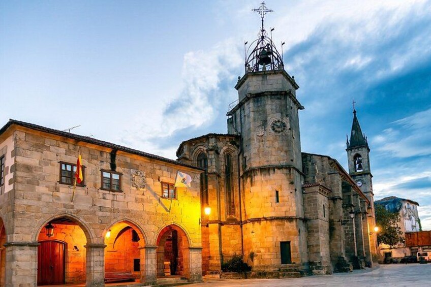A historic stone building with a clock tower, arched doorways, and a bell tower. 5