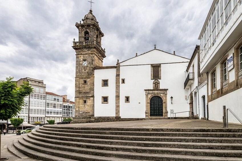 A historic church with a bell tower, steps leading up to the entrance, and a white building with a black door. 4
