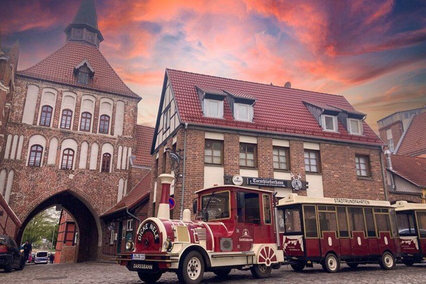A vintage tram, a brick building with a pointed roof, and a street with a cobblestone surface. 2