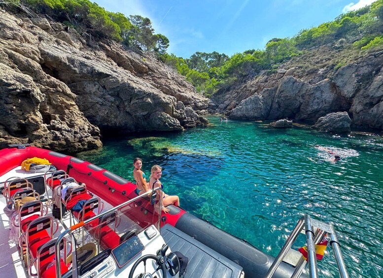 A red inflatable boat with passengers and a rocky coastline. 2
