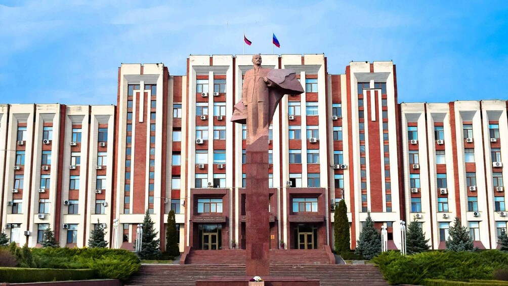 Un grand bâtiment doté d’une statue centrale, de nombreuses fenêtres et de deux drapeaux au sommet. 1