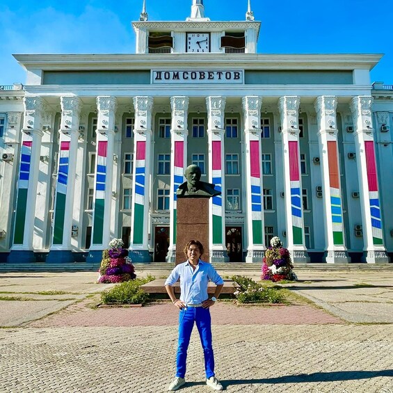 A person standing in front of a building with columns and a clock tower. 3