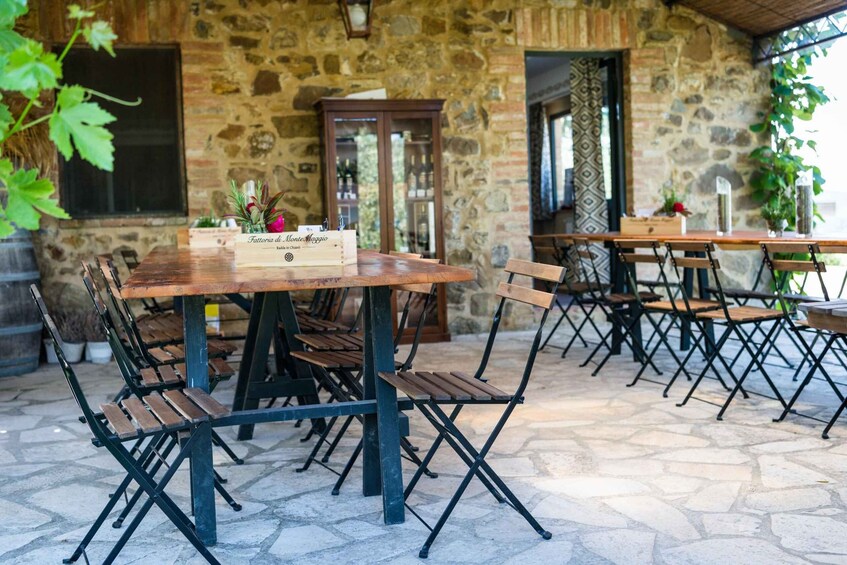 An outdoor patio with stone walls, wooden tables, and foldable chairs. 2