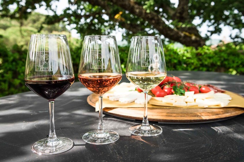 Three wine glasses on a table with a cheese board in the background. 1