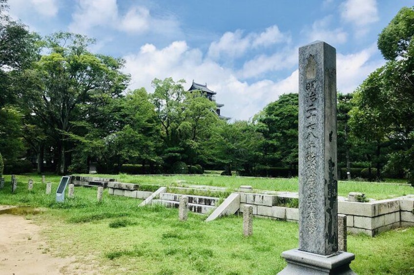 A traditional Japanese stone monument in a park with a pagoda in the background. 5