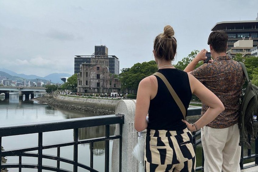 A river with a bridge, a building, and a person taking a photo. 2
