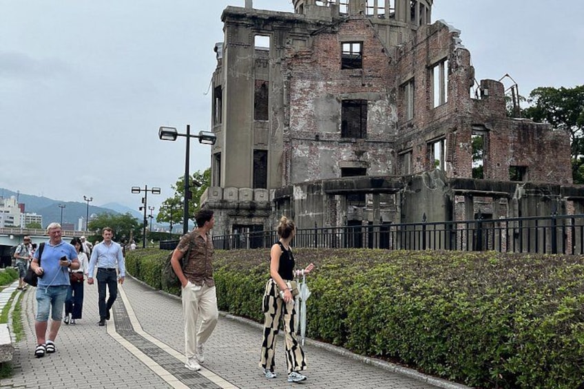 A group of people walking on a paved path beside a historic building with visible damage. 2