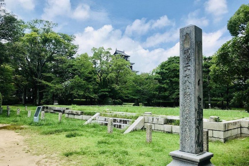 A traditional Japanese stone monument in a park with a temple in the background. 4