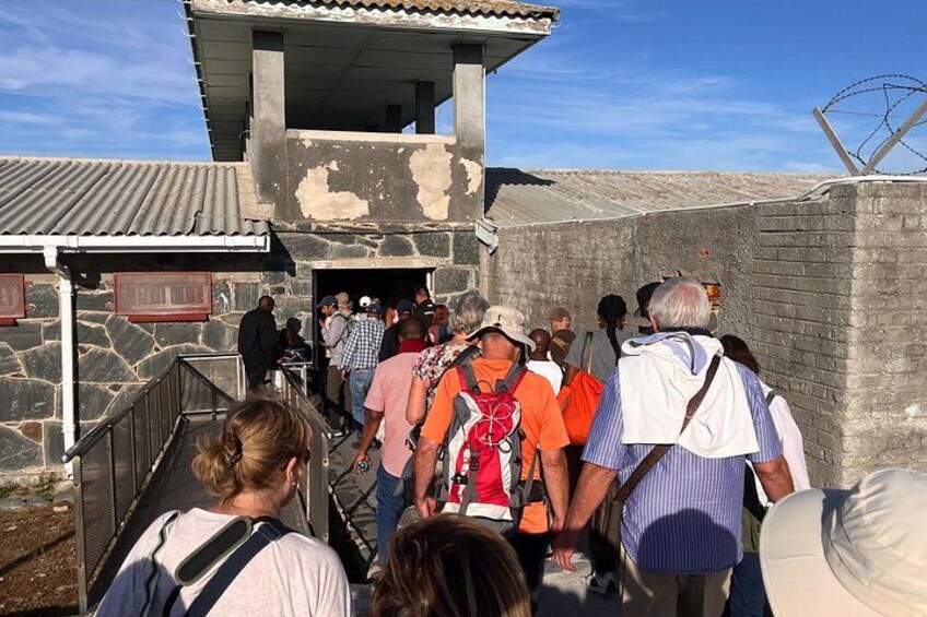 Un grupo de personas sube por una escalera de piedra hacia un edificio con techo de chapa corrugada. 2