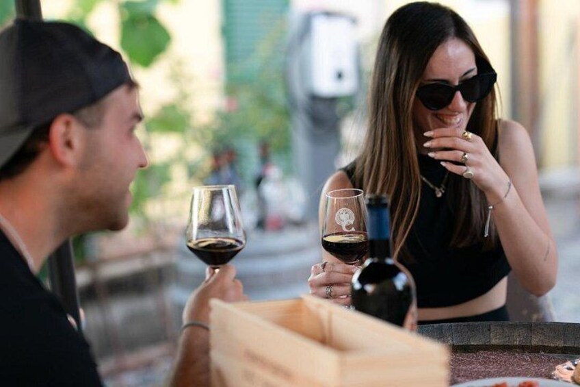 Dos personas sentadas en una mesa al aire libre con copas de vino y una botella. 4