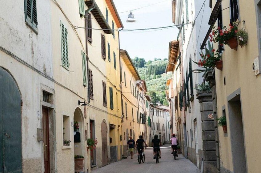 Una calle estrecha flanqueada por edificios, algunos con balcones y macetas con flores. 2