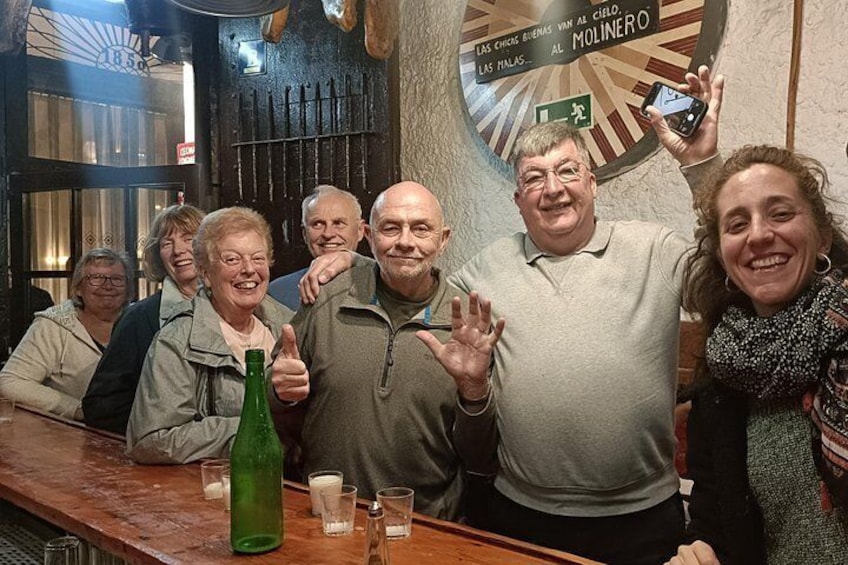 Eine Gruppe von Menschen in einer Bar mit einer Dartscheibe und einem Schild, auf dem 'Las Chicas Bienvenidos al Molinero' steht. 4