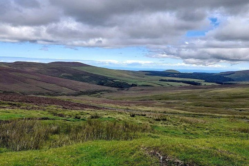 Rolling hills, grassy fields, and a cloudy sky. 3