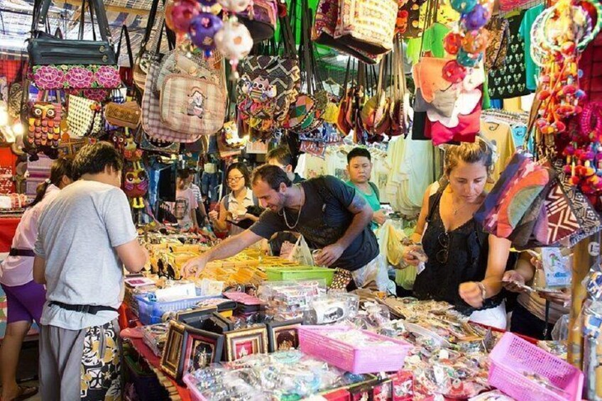 A bustling market with various stalls selling colorful bags and accessories. 2