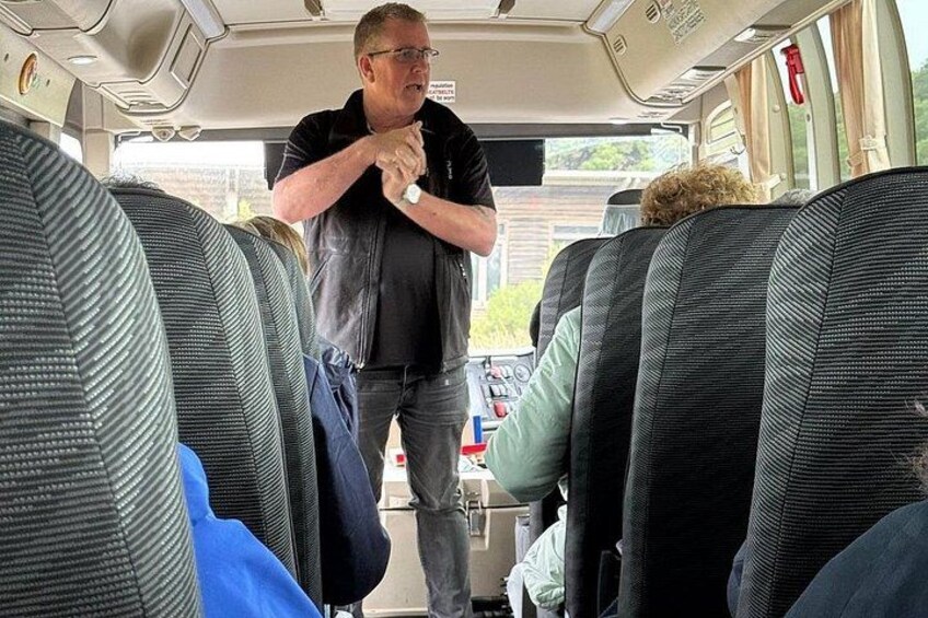 A bus interior with a person standing near the back, a dog on a seat, and a blue bag on the floor. 3