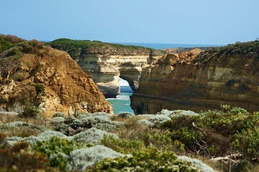 A coastal landscape with cliffs, a narrow water passage, and sparse vegetation. 3