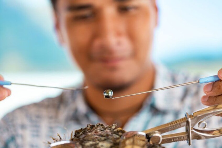 A person holding a magnifying glass and a pair of tweezers, examining a small object closely. 4