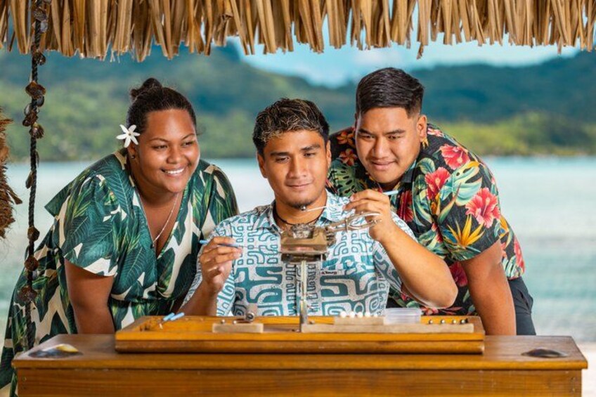 Three people at a wooden table with a tropical backdrop. 1