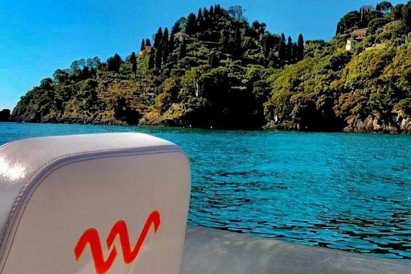 Un barco con un logotipo en la proa, agua tranquila y una ladera boscosa al fondo. 5