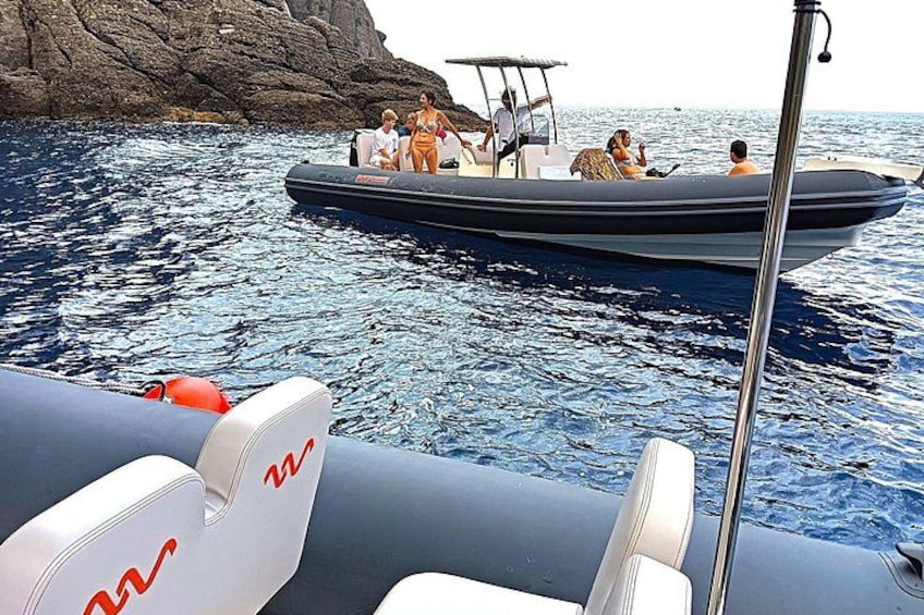 A boat with people on it near a rocky coastline. 4