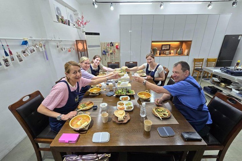 Un grupo de personas reunidas alrededor de una mesa con comida, bebidas y una computadora portátil. 4