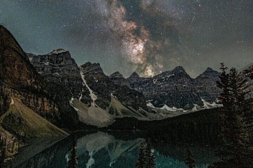 Cielo estrellado sobre una cadena montañosa, con un lago que refleja la Vía Láctea. 1