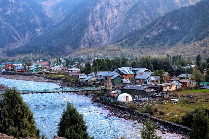 A river flowing through a village with houses and a bridge. 2