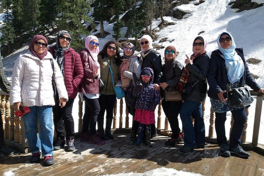 A group of people standing on a wooden deck with snow in the background. 5