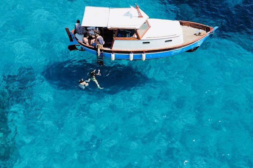 A boat with people on board and a diver in the water. 4