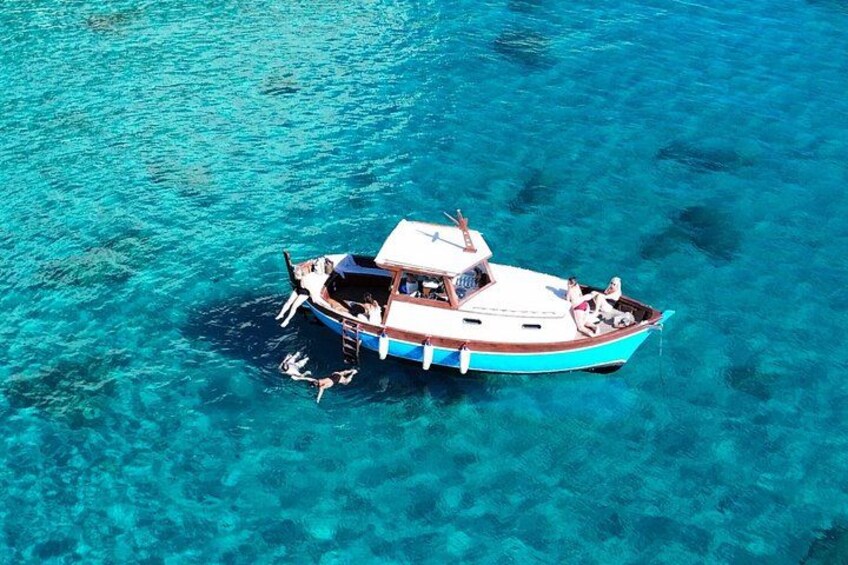 A boat with people on a clear blue sea. 2