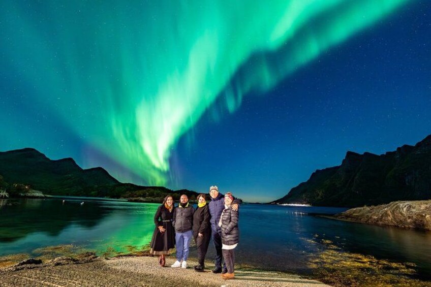 A group of people standing by a lake with the Northern Lights in the background. 4